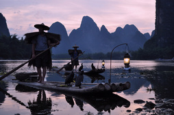 Photo taken on a photography tour of xingping featuring two cormorant fishermen on a bamboo raftamboo raft at sunset